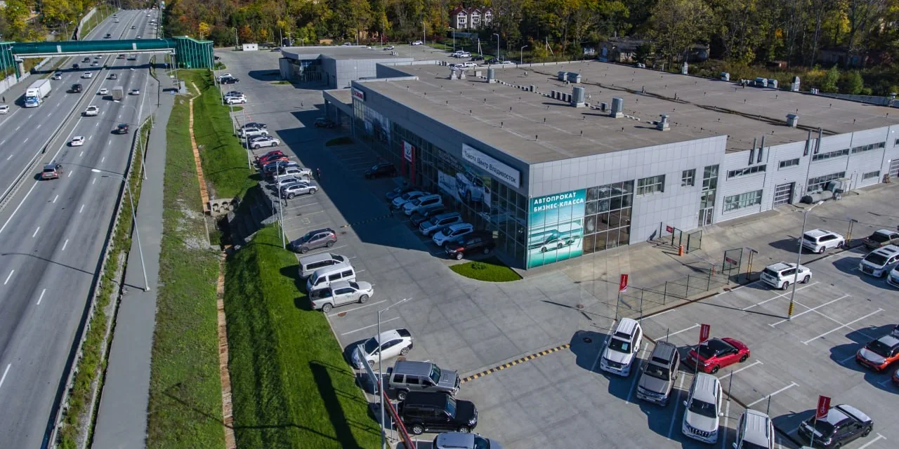 Дилерский центр Summit Motors во Владивостоке с высоты: здание центра и парковка, заставленная автомобилями